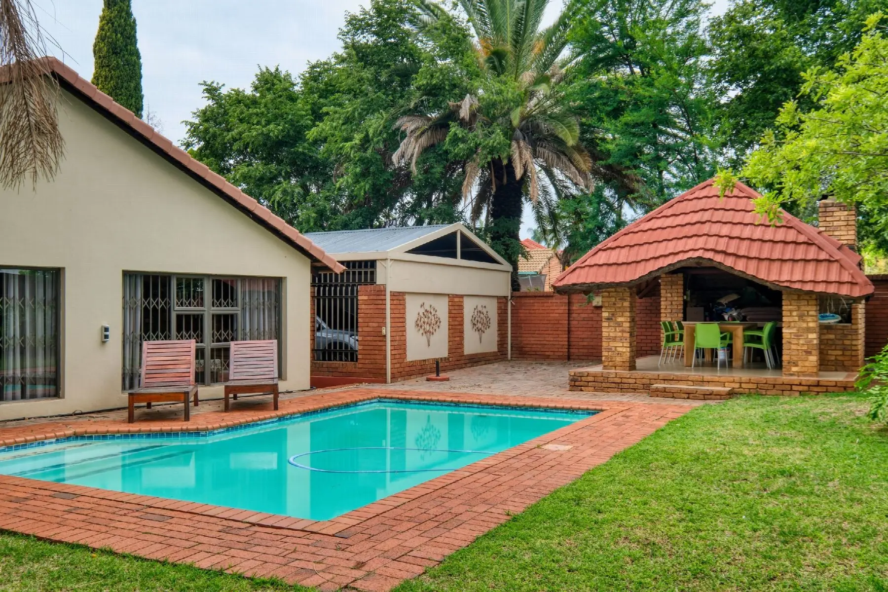 A family home with a swimming pool and a brick lapa in the back garden